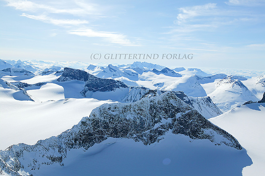 Utsikt fra Galdhøpiggen en marsdag i sørvestlig retning med Storjuvtinden (2344 moh.) som nærmeste nabo. Bukkehøe (2314 moh.) litt lenger bak er også karakteristisk.