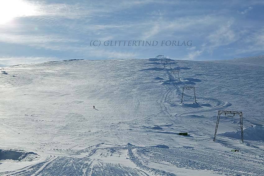 Skikjører på vei ned alpinbakken ved Juvvatnet i mars. Selv om sesongåpningen er mange uker unna, prepareres bakken bl.a. for å holde på snøen.