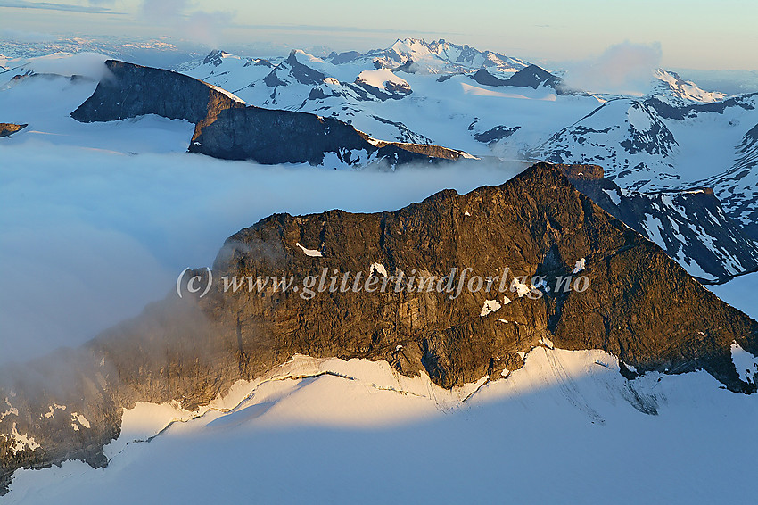 Kveldslys på Storjuvtinden (2344 moh.) sett fra Galdhøpiggen. Bakenfor Bukkehøe (2314 moh.) lett gjenkjennelig, etterfulgt av Smørstabbtindane og Hurrungane.