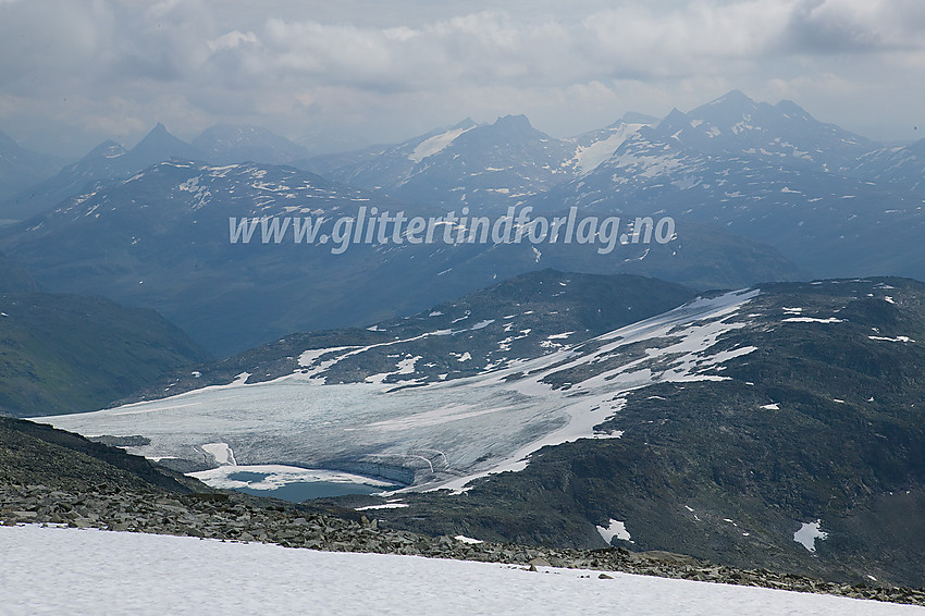 Innunder toppen av Fannaråken med utsikt innover Jotunheimen. Sagi ses sentralt i bakgrunnen, med den spisse Mjølkedalstinden til venstre og Uranosbreen og -tinden til høyre.