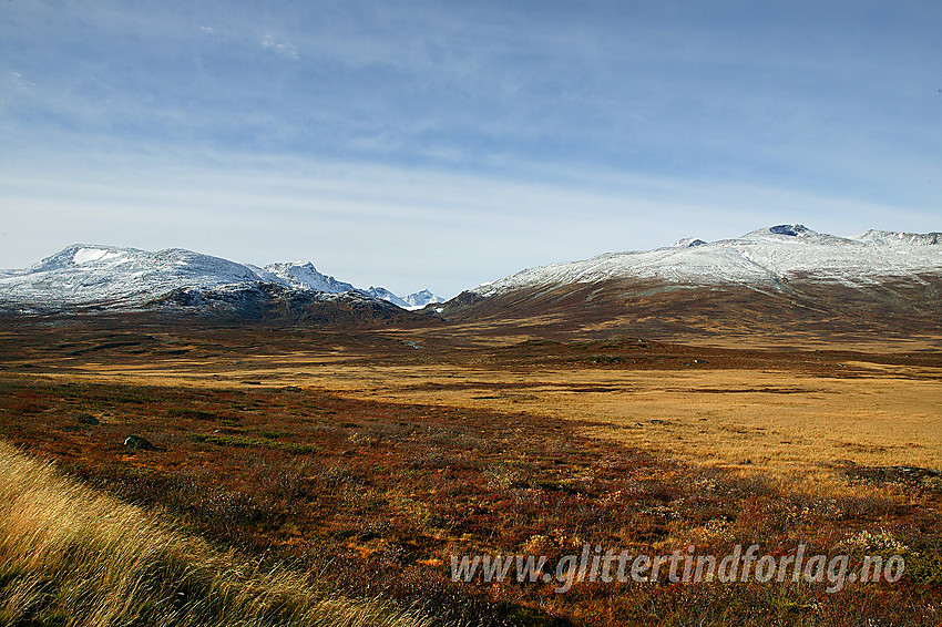 Høstdag nord for Valdresflye med utsikt innover Leirungsdalen og til tindene på begge sider. Nysnøen har lagt seg i høyden og høstfargene har inntatt vegetasjonen.