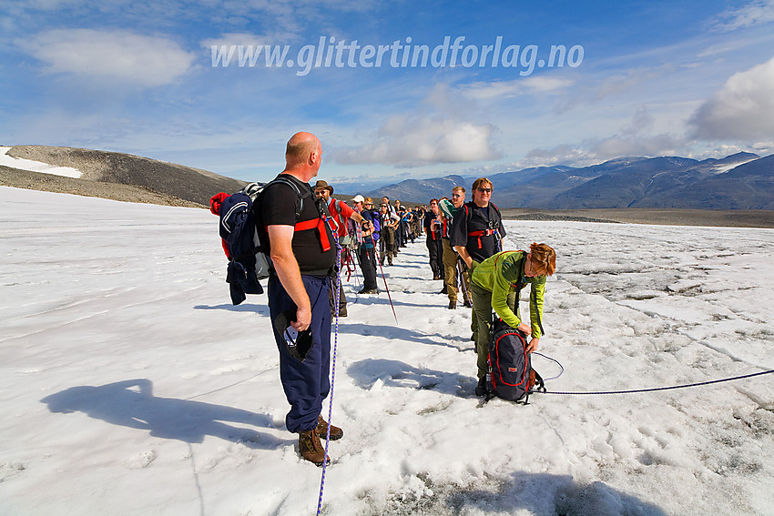 Guided tur over Styggebrean mot Galdhøpiggen. Førerne unner lagene et lite pust i bakken midt på breen. Utsikten, her nordøstover tilbake der vi kom fra, er upåklagelig på en nydelig sommerdag som denne.