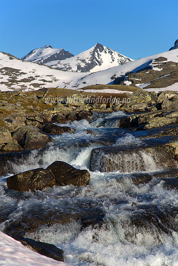 Ved Bandet i Leirdalen danner utløpet av tjerna like vest for veien noen småfosser. I bakgrunnen ses Skarddalstinden (til høyre) og Skarddalseggje (til venstre).