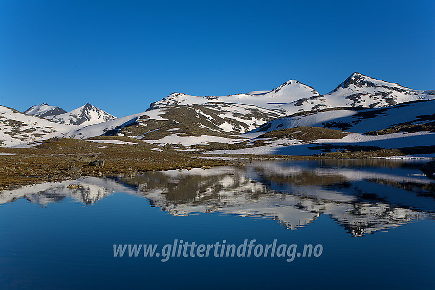 I Leirdalen like før Leirvassbu ved noen små vann vest for veien. Midtre Høgvagltinden (2066 moh, til venstre) og Vestre Høgvagltinden (1967 moh, til høyre), dominerer i høyre bildedel, mens Skarddalstinden og Skarddalseggje gjenkjennes i bakgrunnen til venstre.