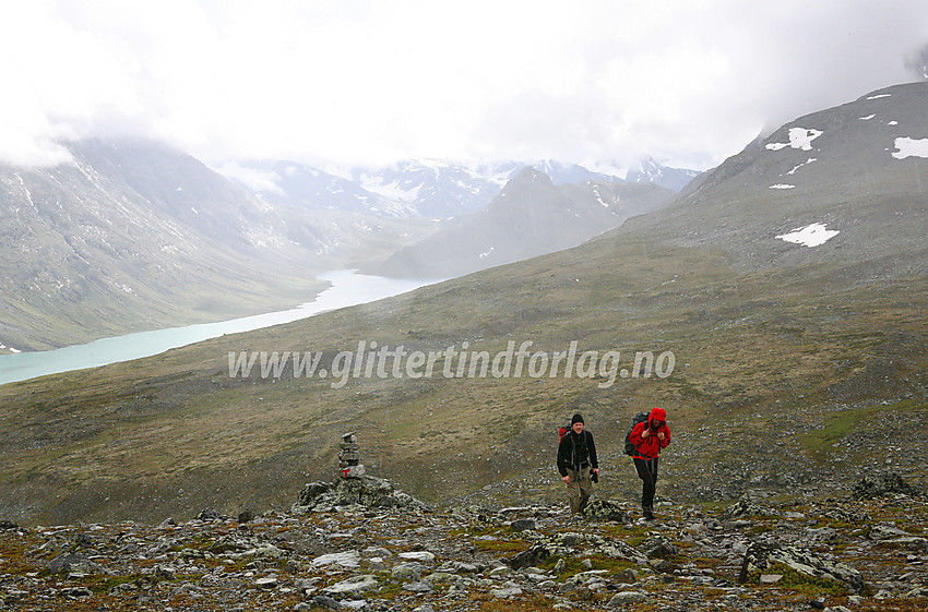 På ruta mellom Glitterheim mot Memurubu/Gjendesheim/Bessheim i pøsregn. Russvanet ses i bakgrunnen, med Gloptindens spisse profil til høyre så vidt under skyene.