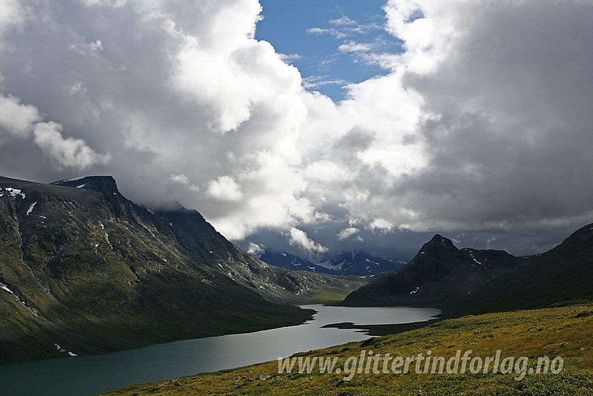 Fra ruta mellom Glitterheim og Memurubu i lia ovenfor Russvatnet med den spisse Gloptinden (1678 moh) til høyre, mens Besshøemassivet reiser seg bratt inni skyene til venstre.