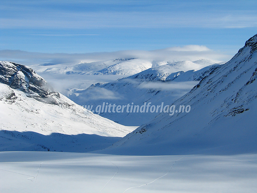 Morgenstund utenfor snøhula på Tverråbrean innunder Nørdre Bukkeholstinden med utsikt mot Visdalen med Spiterhøe (2033 moh) til høyre og Skauthøe (1933 moh). Bakenfor ruver Glittertinden med toppen i tåka.