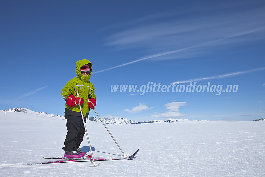 Liten skiløper lener seg på skistavene under en tur på Valdresflye. I bakgrunnen ses bl.a. Besshøe (2258 moh).