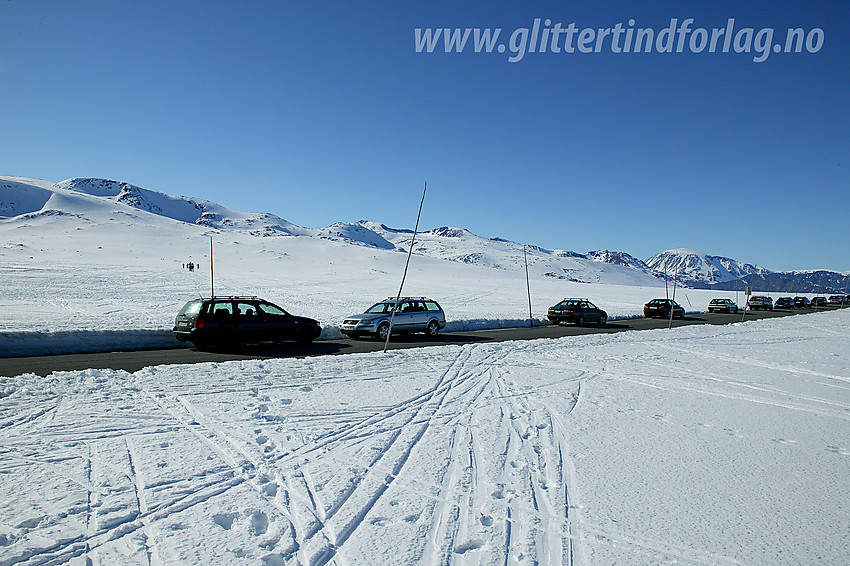 Lang rekke med biler parkert på toppen av Valdresflye. Folk strømmer til for å nyte herlige vårskiturer.