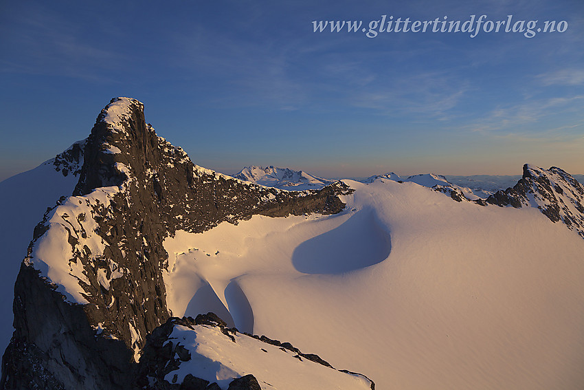 Utsikt fra Veslebjørn Nord (2110 moh) bortetter den smale Bjørneggen i retning Veslebjørn (2150 moh) og videre bort til Skeie (2118 moh helt til høyre). I det fjerne ses bl.a. Hurrungane og Fannaråken. I forgrunnen til høyre Leirbrean med store vindgryter.