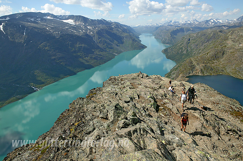 Fjellvandrere på vei opp den siste del av selve Besseggen med Gjende og Bessvatnet i bakgrunnen.