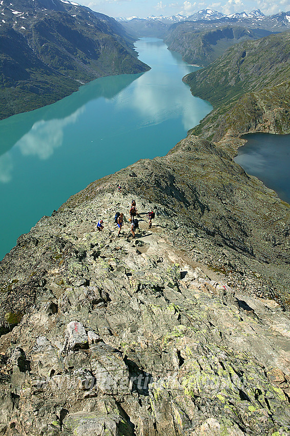 Fjellvandrere på vei opp Besseggen med Gjende og Bessvatnet i bakgrunnen. Besseggen har i hovedsak to små klyvepassasjer. Den øverste av disse ses helt i forgrunnen, mens den andre er litt lenger nede bak gruppa på bildet.