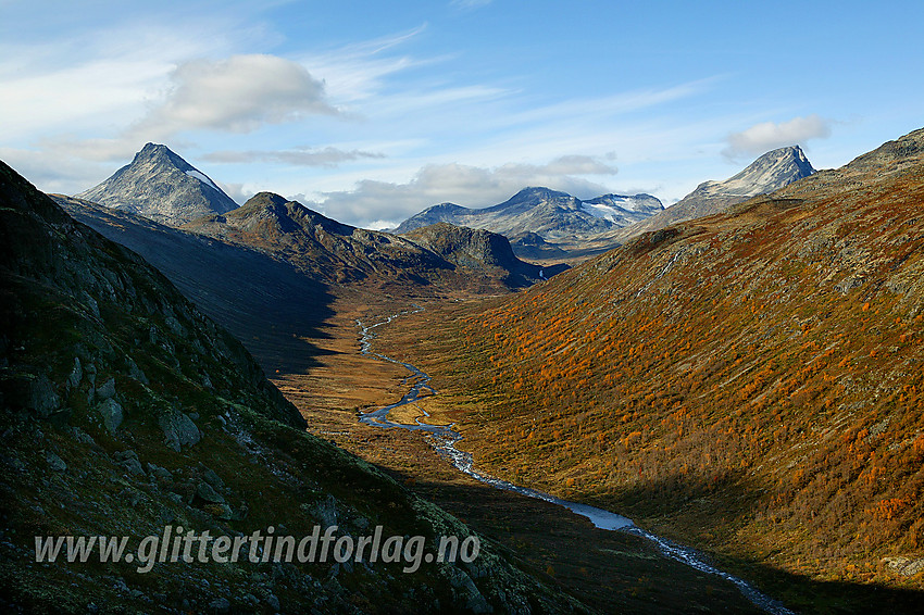 På vei opp normalveien mot Gjendetunga fra øst med utsikt nordvestover opp Storådalen mot Hellerkampen og Hellerfossen. Bak, helt til venstre ses den kvasse Skarddalseggje. Andre topper i bakgrunnen er: Langvasshøe, Visbreatinden, de sørvestlige Urdadalstindane og Semeltinden.