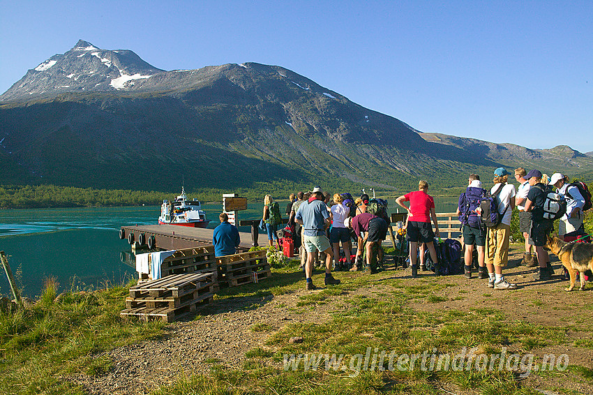 Fjellvandrere venter på båtskyss fra Gjendebu østover Gjende. I bakgrunnen ses Nørdre Svartdalspiggen (2137 moh).