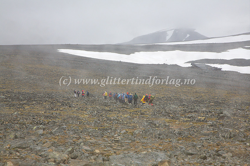 En gruppe på vei mot Galdhøpiggen en ufyselig sommerdag. Bildet er tatt fra peisestua på Juvashyta. Bak til høyre i tåka ses litt av Svellnose.