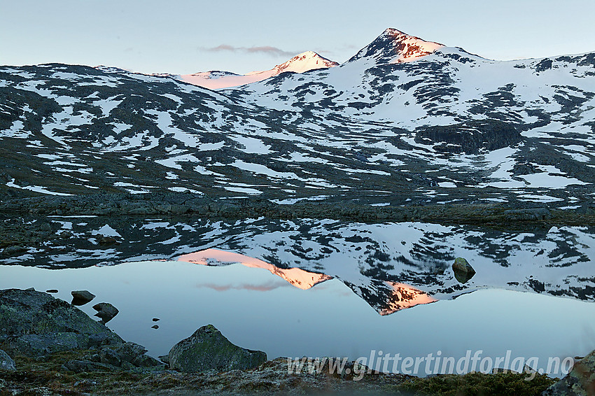 Høgvagltindane speiler seg i et lite tjern i Gravdalen en sommerkveld.