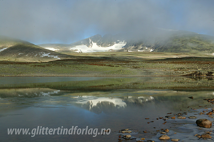 Ved det vesle tjerne nær Snøheim med Snøhettamassivet delvis skjult av morgentåke i bakgrunnen.