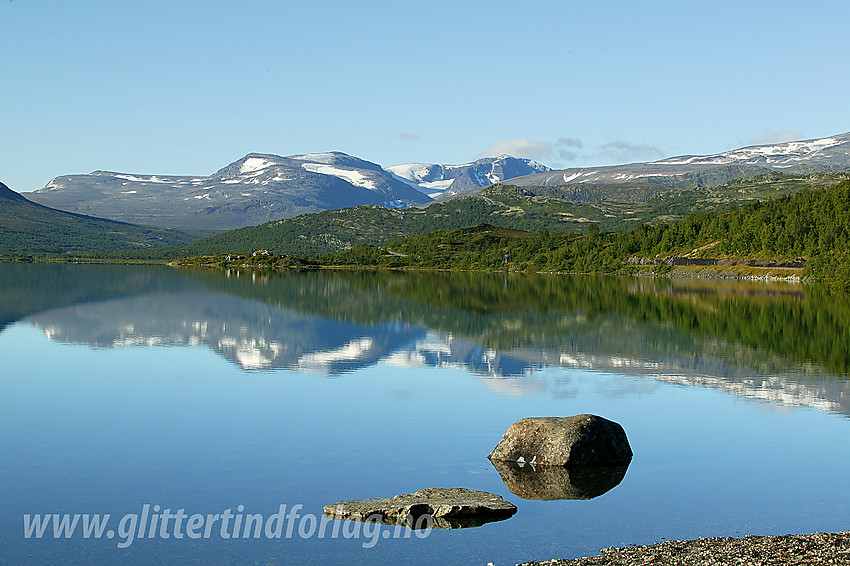 Ved Øvre Sjodalsvatnet en blikkstille sommermorgen. I bakgrunnen bl.a. Rasletinden og Munken.