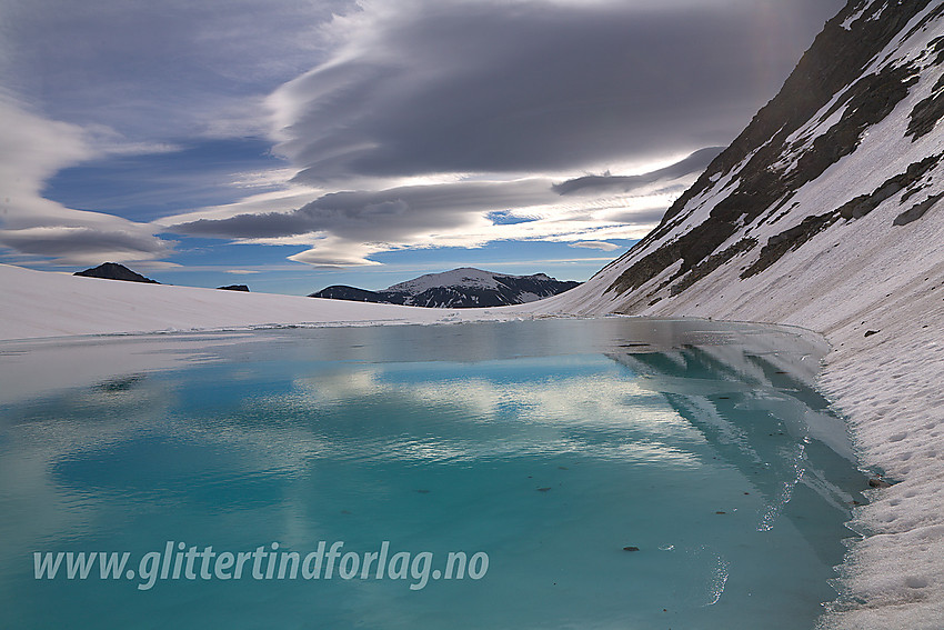 Ved et oppdemt brevann på Vestre Memurubrean innunder nordveggen på Hinnåtefjellet. I bakgrunnen ses Surtningssue (2368 moh).