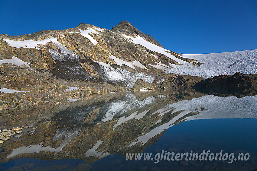 Ved et lite brevann som har smeltet frem ved fronten av Uranosbreen (på litt eldre kart er det tegnet inn isbre her). I bakgrunnen ruver sørryggen på Uranostinden med Uranostinden S2 (2048 moh) som det spisse punktet øverst på eggen. Selve Uranostinden ses såvidt i bakgrunnen.