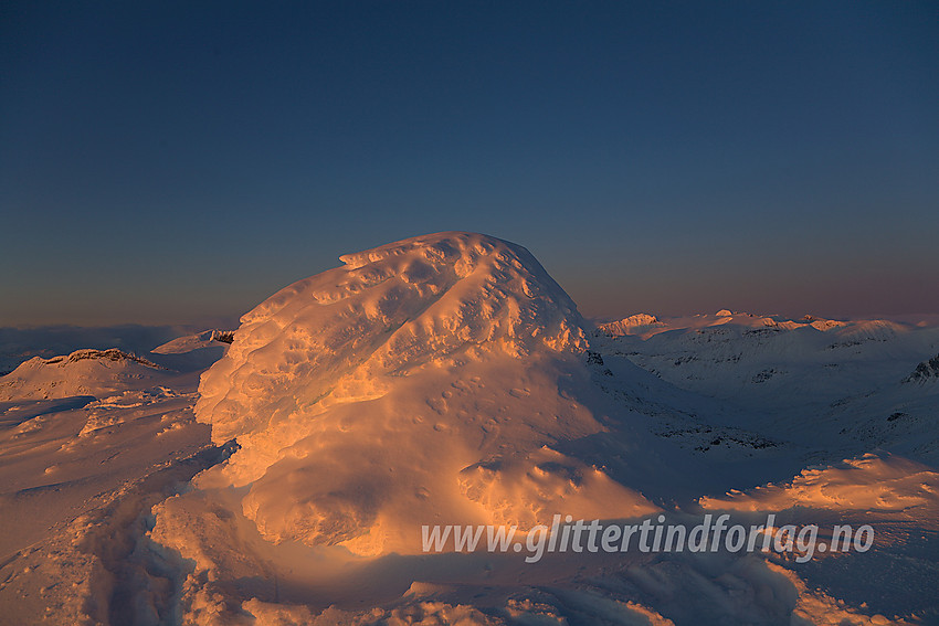 Den nedsnødde varden på Gravdalstinden (2113 moh) i solnedgang.