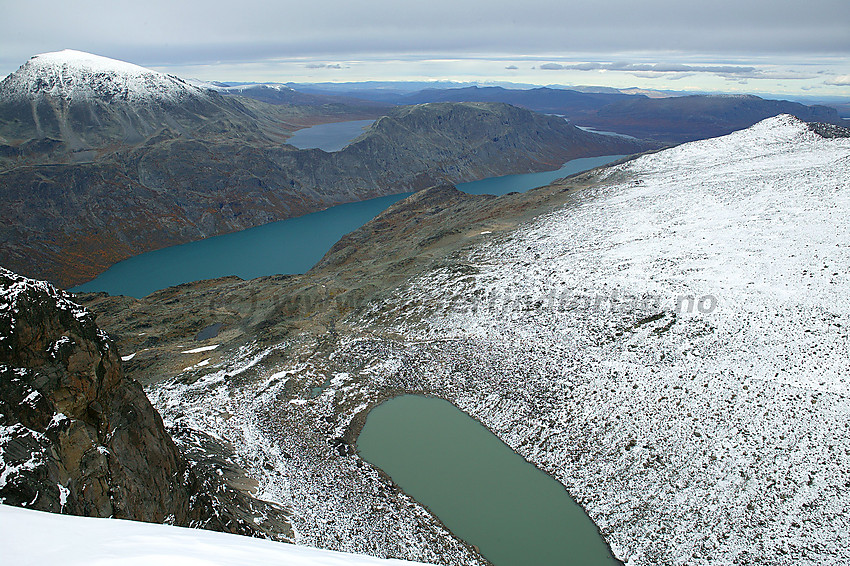 Flott utsikt fra Eggen en overskyet høstdag mot Besshøe, Gjende, Bessvatnet og Veslfjellet. I det fjerne anes Rondane bak Veslfjellet. I forgrunnen et bregrønt tjern under østveggen.