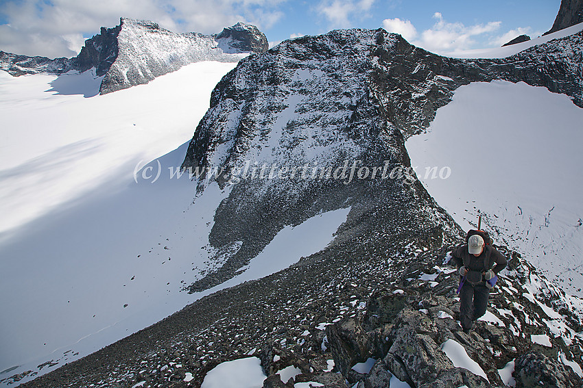 På vei nordover på fjellryggen mellom Skardstinden og Storgrovhøe. Rett bak personen Søre Heimre Illåbreatinden (2175 moh.) og bak til venstre Storjuv- (2344 moh.) og Ymelstinden (2304 moh.).
Breen til venstre er Storjvubrean og breen til høyre er Heimre Illåbrean.