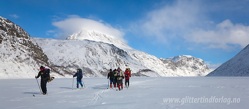 Gruppe skiløpere på vei over Gjende. Her like vest for Memurubu. I bakgrunnen bl.a. Besshøe med skydott på og Veslfjellet pluss Besseggen.