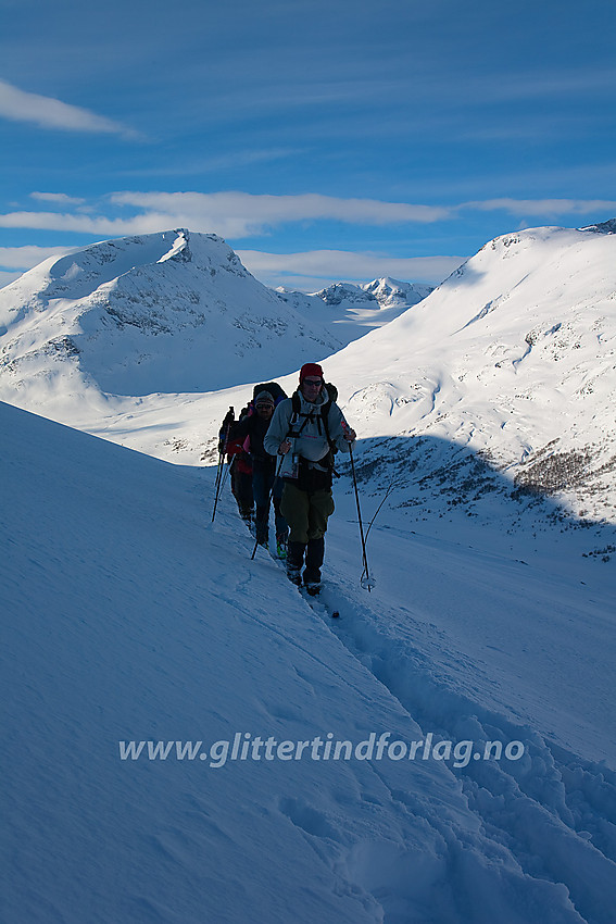 Skiløpere på vei fra Spiterstulen mot Glitterheim. Den første lange kneika fra Visdalen mot Skautflye er snart unnagjort. I bakgrunnen Tverrådalen, Styggehøe og Nørdre Bukkeholstinden.