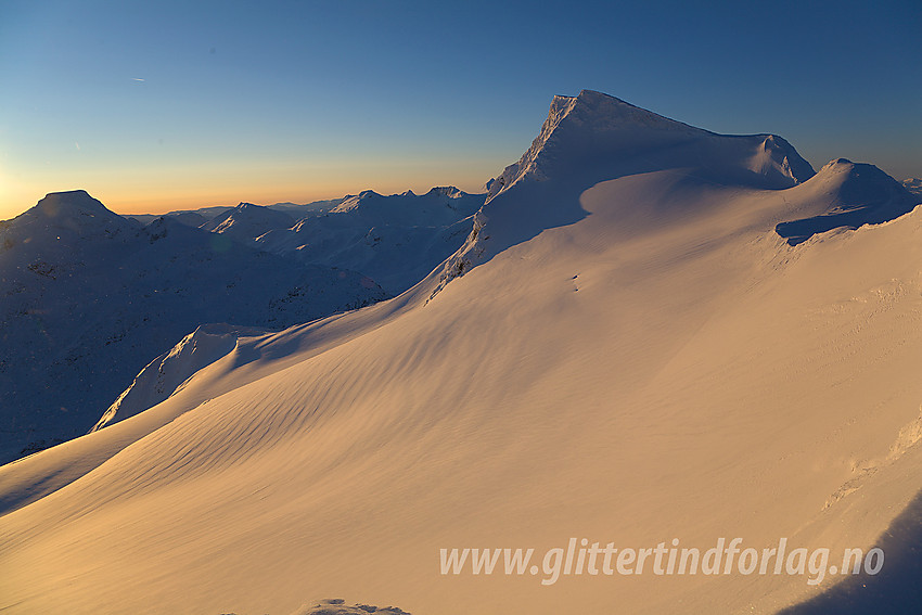 Gravdalstinden (2113 moh) tar seg flott ut fra nord og nordøst. Store Rauddalstindens (2157 moh) silhuett ses bak til venstre.