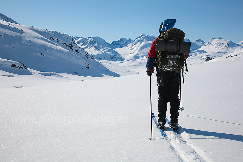 Skiløper på vei ned Memurudalen med Gjendealpene i bakgrunnen.