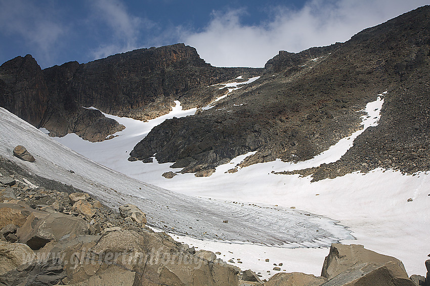 Surtningssues Sørtopp (2302 moh) med den vesle breen på sørsiden i forgrunnen. Via breen og senere ura (der en snøstripe strekker seg oppover) kommer man seg greit opp på ryggen øst for Sørtoppen.