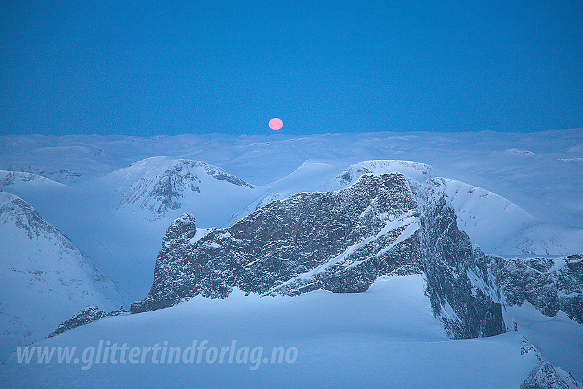 Vinternatt på Galdhøpiggen med utsikt mot Skardstinden. Fullmånen er i ferd med å skli ned bak Jostedalsbreen.