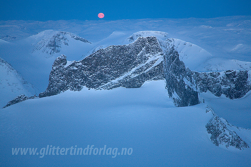 Vinternatt på Galdhøpiggen med utsikt mot Skardstinden. Fullmånen er i ferd med å skli ned bak Jostedalsbreen.