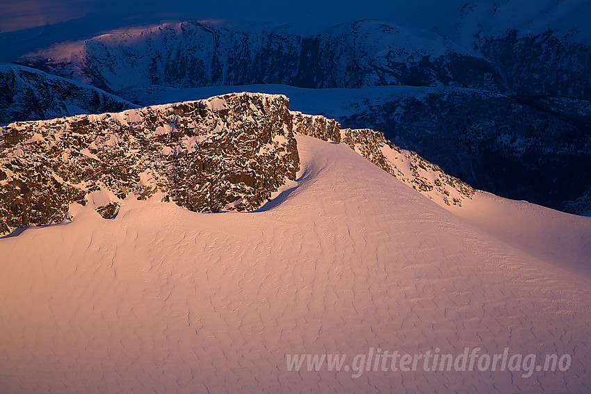 Nordryggen på Vesle Galdhøpiggen sett fra Galdhøpiggen med Løftet til høyre i bildet. De lavere fjellene i bakgrunnen ligger fortsatt i "natteskyggen".