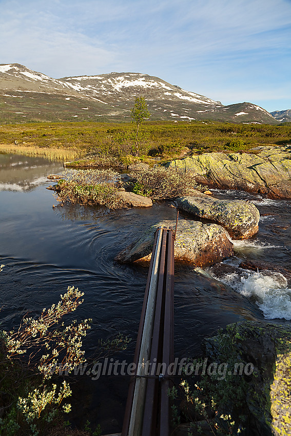 Ved utløpet av Trolltjernet med Veslebotnskarvet i bakgrunnen. Her er en bro i form av en stålbjelke.