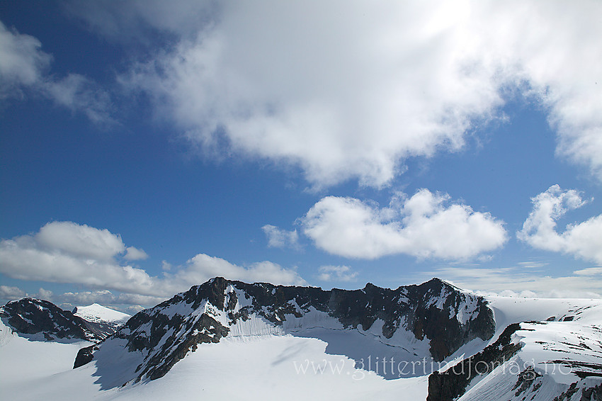 Toppryggen på Store Memurutinden sett fra nord. Østtoppen (2367 moh.) til venstre, Midttoppen (2364 moh.) litt til høyre for midten og Vesttoppen (2365 moh.) til høyre. I bakgrunnen til venstre ses Austre Memurutinden og Surtningssue.