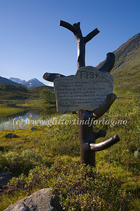 Forseggjort informasjonsskilt like ved riksvei 55 nær Jotunheimen Fjellstue med informasjon om fisking. I bakgrunnen anes noen av Tverrbottindane.