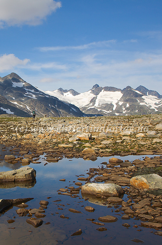 Høyfjellstemning like øst for Leirvassbu mot  Stetinden og en rekke av Smørstabbtindane, med fjellvandrer på vei vestover.