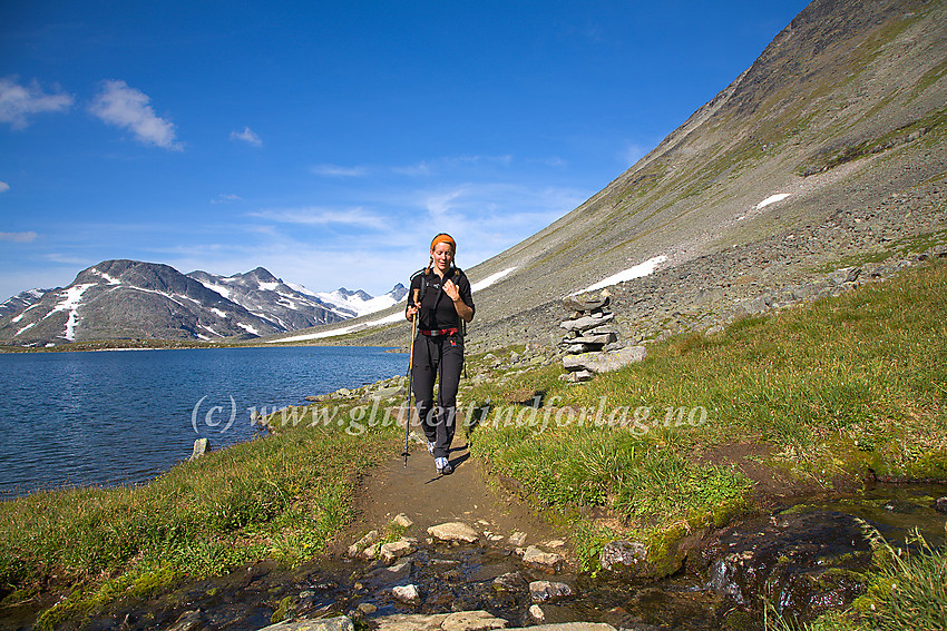 Fjellvandrer på vei østover stien gjennom Kyrkjeglupen med fjellvannet Troget til venstre. Sentralt i bakgrunnen ses Stetinden (2020 moh.)