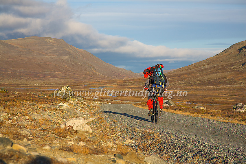 Med sykkel på vei ned grusveien fra Glitterheim til parkeringen ved nasjonalparkgrensa. I bakgrunnen Heranoshøe (1666 moh.)