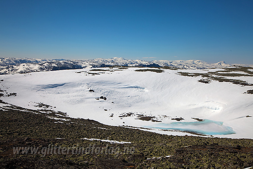 Snøfonner ned mot Nordlandstjednet sett fra toppen på Skutshorn. I det fjerne hever Høgeloft, Sulefjellet og Suletinden seg.