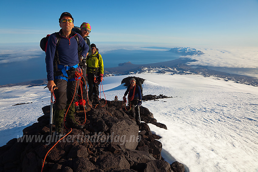 På en liten bergrabb på vei mot toppen. Nunataken 100 meter i bakgrunnen og i det fjerne Sør Jan.  Havtåka stanger mot fjellene fra høyre og det åpner seg et skyfritt belte på andre siden av øya.