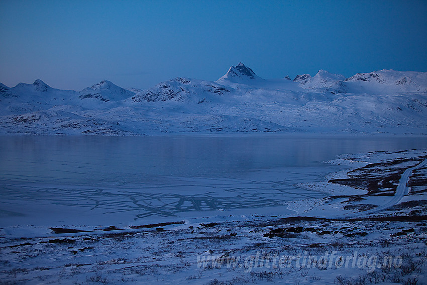 Nede ved Tyin etter solnedgang. Tyins islagte speil i forgrunnen og Uranostinden sentralt i bakgrunnen.