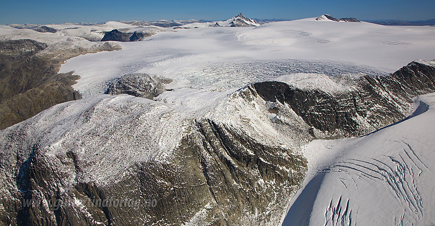 Kjenndalskruna i forgrunnen med toppen like utenfor høyre bildekant. Krunebreen rett bak der og så Jostedalsbreen videre innover mot Brenibba og Lodalskåpa.