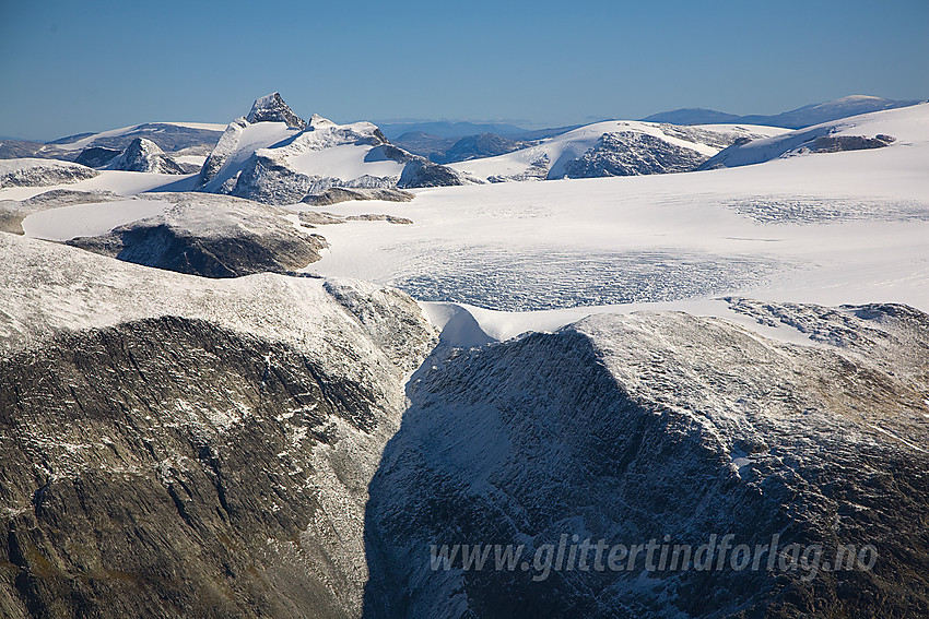 I forgrunnen rota på Bødalsfjellet etterfulgt av øvre del av Bødalsbreen med Lodalskåpa lett gjenkjennelig litt til venstre for midten. Kulen i bakgrunnen er Raudskarvfjellet.