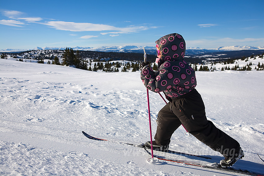 Liten skiløper på vei mot Smørlifjellet med flotte fjellpanoramaer i bakgrunnen.