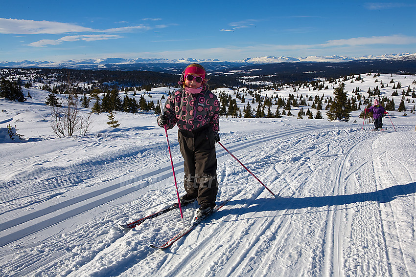 Liten skiløper på vei opp bakkene mot Smørlifjellet med herlige utsyn i bakgrunnen.