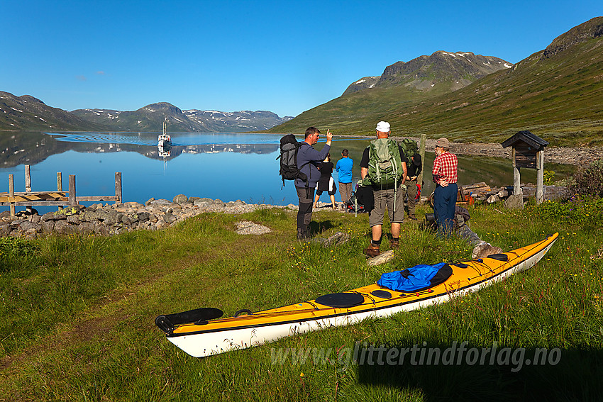 Gruppe passasjerer venter på M/B Bitihorn ved brygga på Torfinnsbu en flott sommermorgen.