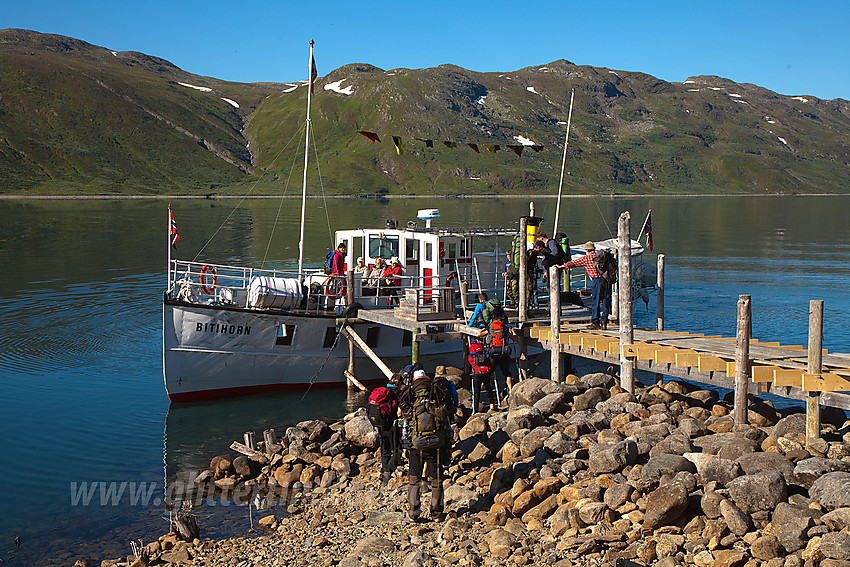 Passasjerer går ombord i M/B Bitihorn ved brygga på Torfinnsbu en flott sommermorgen.